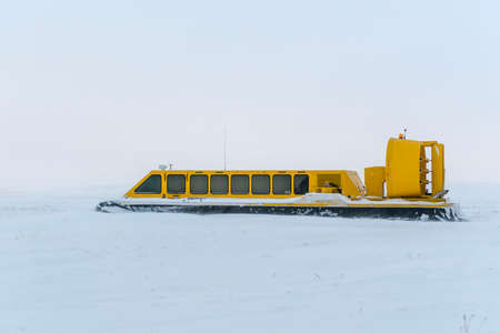 Hovercraft in winter tundra. Air cushion on the beach. Yellow hover craft under snow.の写真素材