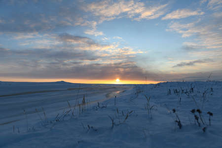 Arctic landscape in winter time. Small river with ice in tundra. Sunset.の写真素材