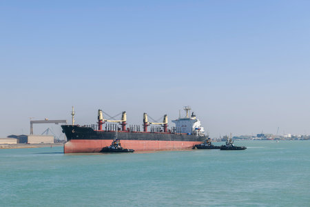 Vessel approaching to berth with tugs assistance. Mooring operations. Bulker. Dry cargo ship.