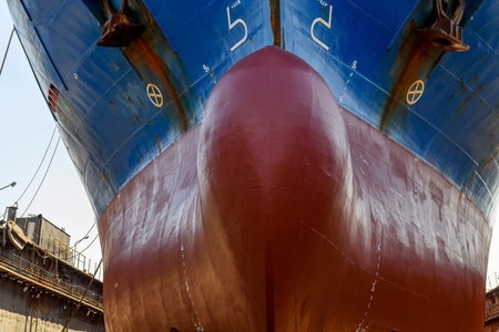 Cargo vessel in dry dock on ship repairing yard. Bulbous bow.