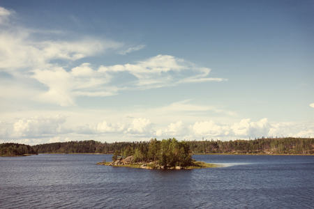 Ladoga lake with small island under summer sunset light panoramic view. Toning effect done with a vintage retro Instagram style filterの写真素材