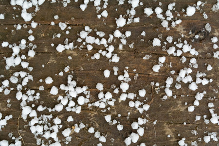 Small white snowflakes of first snow on dirty wooden floor close-up top view