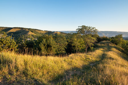 Footpath in hills and mountains near town Kislovodsk in Russia under golden sunrise light in summer...