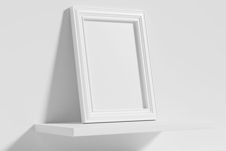 Blank white empty rectangular photo frame on white shelf leaning at empty white wall, diagonal view,...