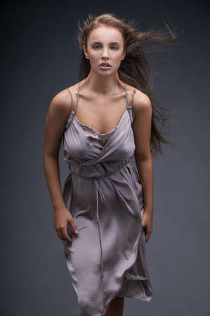 Dark-haired girl in a tight dress resists the flow of the wind.Her hair blazing in the wind, the dress hugs tightly elastic body,and the posture shows the desire to break through the stream.の写真素材