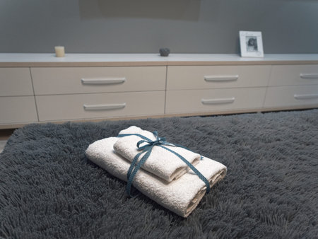 Small white towels folded in half bandaged with a ribbon lie on the bed.の写真素材