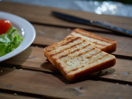 Slices of white bread are fried over an open fire.