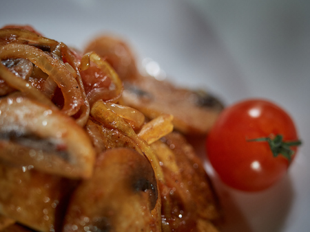 Small cuts of meat cooked along with fried mushrooms and onions are served to the table for dinner.の写真素材