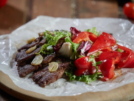 Fried beef pieces are served with garlic and red bell pepper.の写真素材