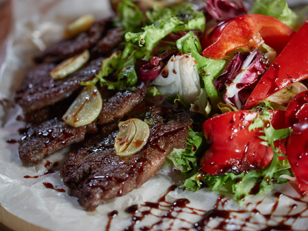 Fried beef pieces are served with garlic and red bell pepper.の写真素材