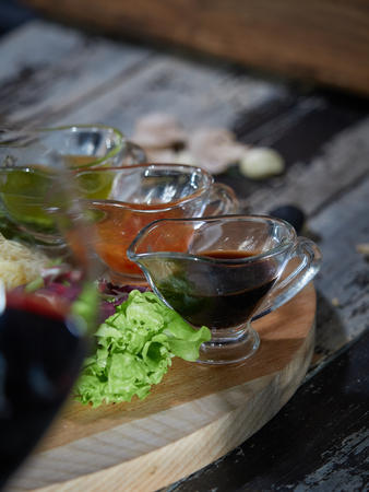 A large piece of raw beef meat is served on a table on a wooden tray with sauces for meat.の写真素材