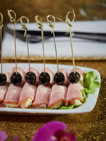 Pork rolls stuffed with cheese and egg. Black olives are put on top of the rolls.の写真素材