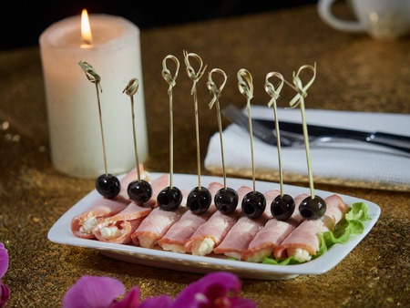 Pork rolls stuffed with cheese and egg. Black olives are put on top of the rolls.の写真素材