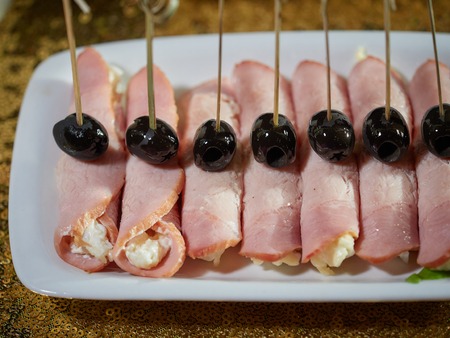 Pork rolls stuffed with cheese and egg. Black olives are put on top of the rolls.の写真素材
