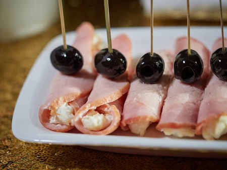 Pork rolls stuffed with cheese and egg. Black olives are put on top of the rolls.の写真素材