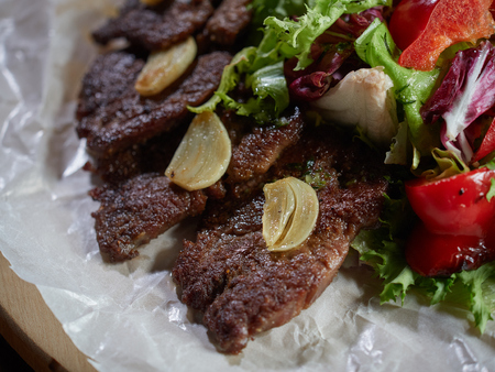 Fried beef pieces are served with garlic and red bell pepper.の写真素材