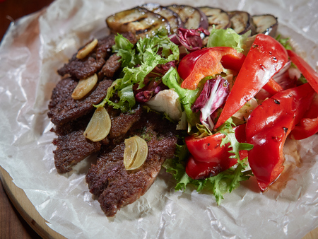 Fried beef pieces are served with garlic and red bell pepper.の写真素材