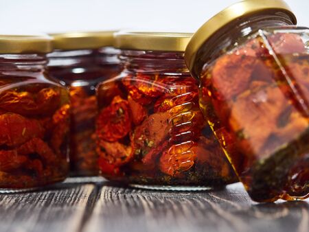 Home-made canned red dried cherry tomatoes are packed in small glass jars.の写真素材