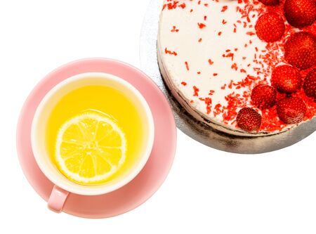 a cup of tea with a single piece of lemon, stands beside chocolate vanilla tortoise decorated with fresh strawberries, on a white backgroundの写真素材