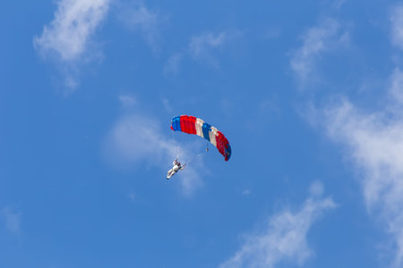 skydiver descends to earth in the clouds and blue sky view from the ground