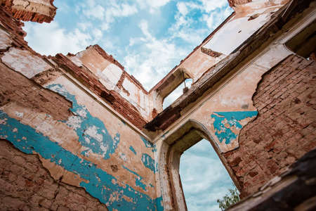 destroyed part of an abandoned brick building in the background of the azure sky and clouds from the bottom upの写真素材