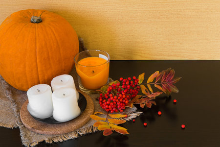 Autumn composition of rowan berries, pumpkins, candles and colorful leaves on the cloth of burlap on white backgroundの写真素材