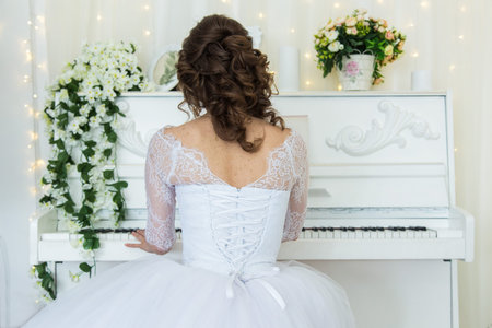 young bride in white wedding dress playing pianoの写真素材