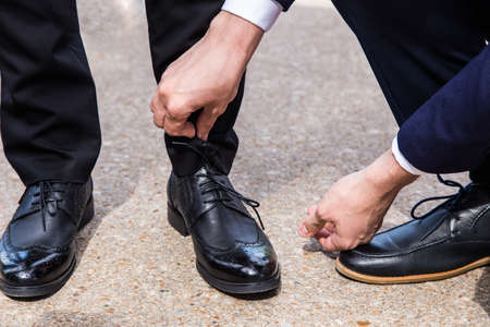 Man ties his shiney new black leather business shoes.の写真素材