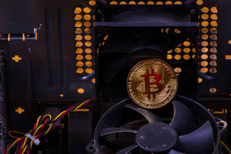 gold coin bitcoin on the motherboard among computer componentsの写真素材
