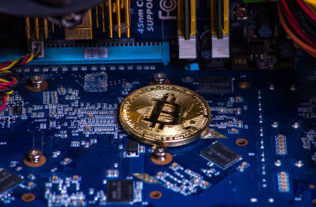 gold coin bitcoin on the motherboard among computer componentsの写真素材