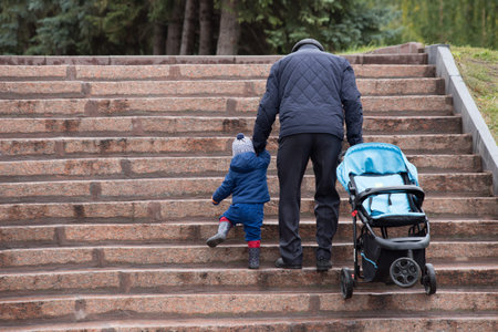 Grandfather with grandson holding hands walking and climbing the stairs.