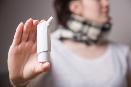 a woman uses a needle throat spray in her mouth on white background. from a sore throat