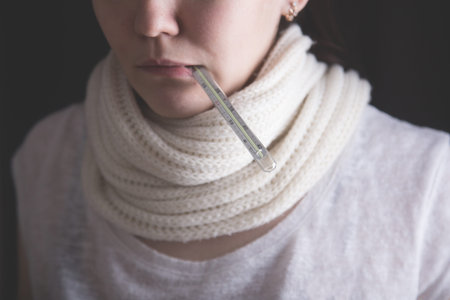 a girl with a scarf around her neck and a thermometer in her mouth. health and disease.