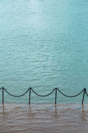 elements of the fence on the flooded pier. black metal bars with chains between them.の写真素材