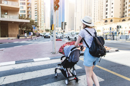 Dubai, UAE February 19, 2018: A young woman with a stroller crosses the road on a pedestrian...