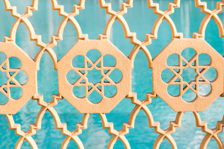 yellow stone ornament in traditional oriental style on the blurred background of azure waterの写真素材