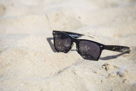 black sunglasses lie on the sand close up. The concept of beach holidays and travelの写真素材