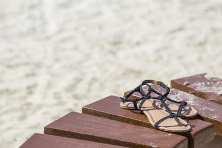 female brown sandals on a wooden table on the beach background. Concept of a summer rest and travelの写真素材