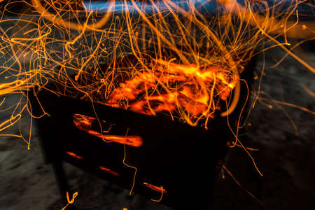 bright orange sparks from a campfire on long exposure and smoldering coals. dynamics lines traces.の写真素材
