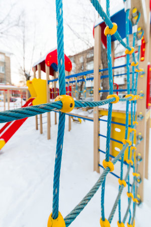 Multicolored children's playground in the courtyard in the winter. wire ropeの写真素材