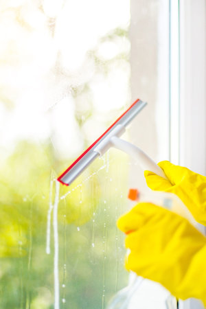 Cleaning concept - hand cleaning glass window pane with detergent and rubber aluminum wiperの写真素材