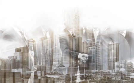 Double exposure. Businessmen shake hands against the backdrop of a modern business city and skyscrapersの写真素材