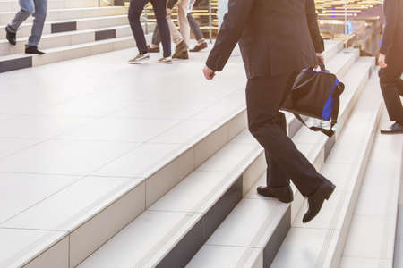 A businessman in a suit with a briefcase climbs the stairs in the business center. The concept of career ladder and successの写真素材