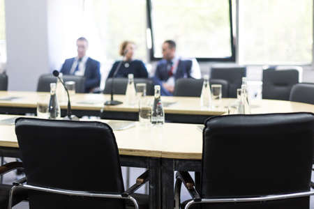 Bottles of water and glasses on the empty meeting table and people in the background. Business conceptの写真素材