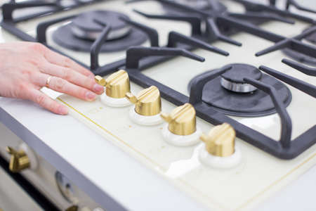 Safe frustration with fire. Modern kitchen stove cook with blue flames burning and woman handの写真素材