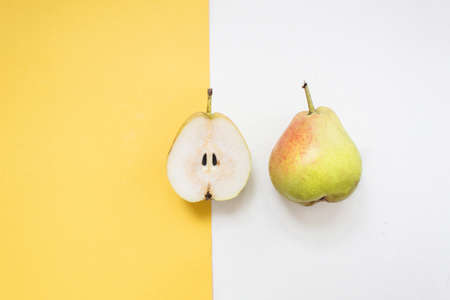 half sliced of yellow pear fruit isolated on yallow and white background. Minimal colorful design concept.の写真素材