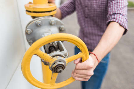 power station worker. man engineer in helmet and shirt twist gas pipe valveの写真素材