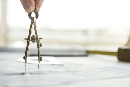 architect builder works at the table with drawings. Helmet, drawings, compasses in the workplaceの写真素材