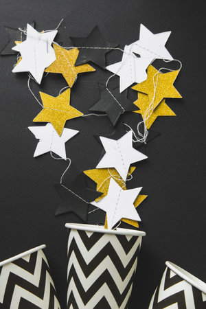 festive decoration of the table for the birthday or christmas party. stylish decorations on a black background, a garland garlands, glasses, gifts. free space for textの写真素材