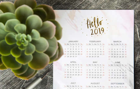Calendar for 2019 on the office desk in a notebook. Plans and goals for the new year. Top view layout on gray backgroundの写真素材